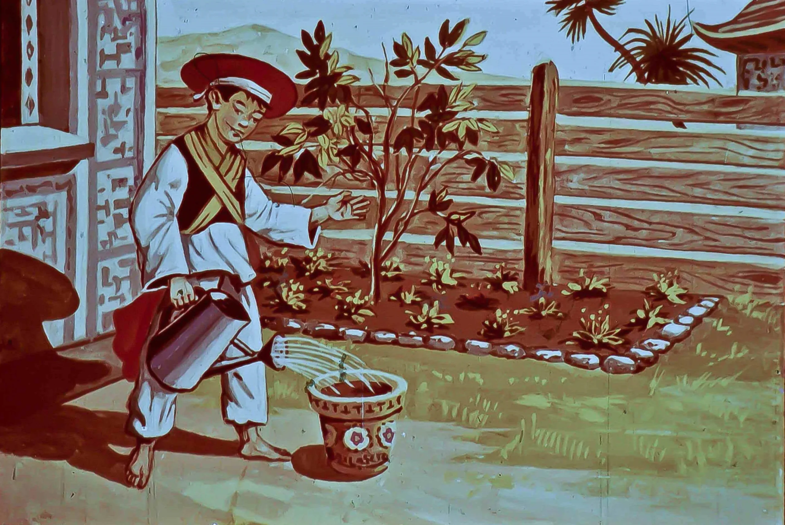 Un băiat în uniformă tradițională udă o plantă dintr-un ghiveci cu un udător, într-o grădină cu flori și copaci.