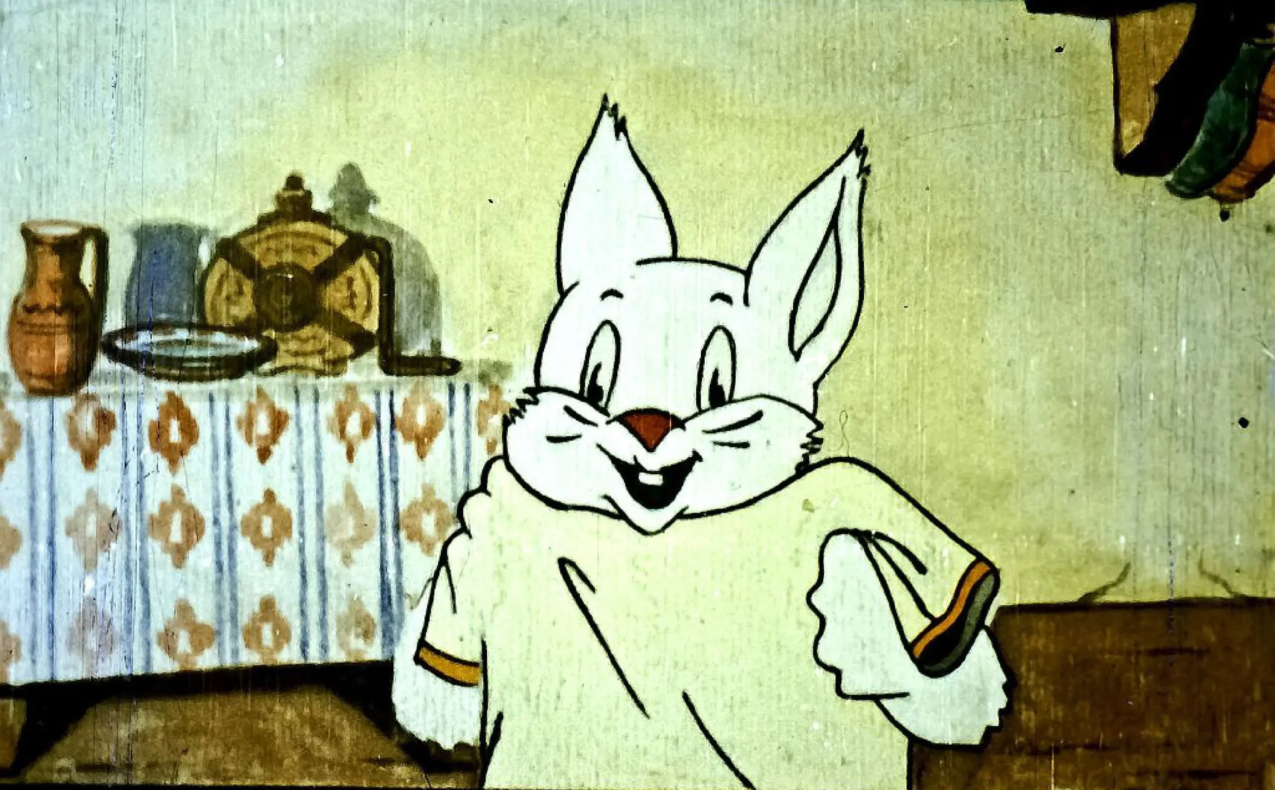 Un personaj cartoon zâmbitor care poartă o bluză, într-o cameră cu mobilier simplu.