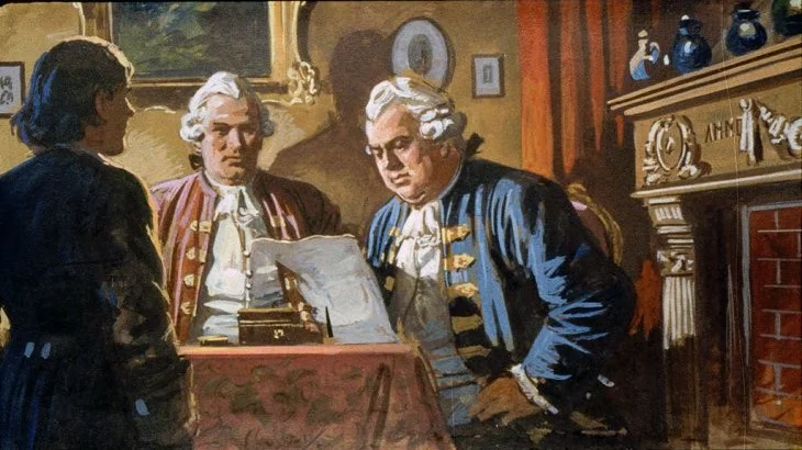 Imagine din interior, trei bărbați îmbrăcați în costume istorice discutând într-o cameră, cu un birou și un document pe masă.