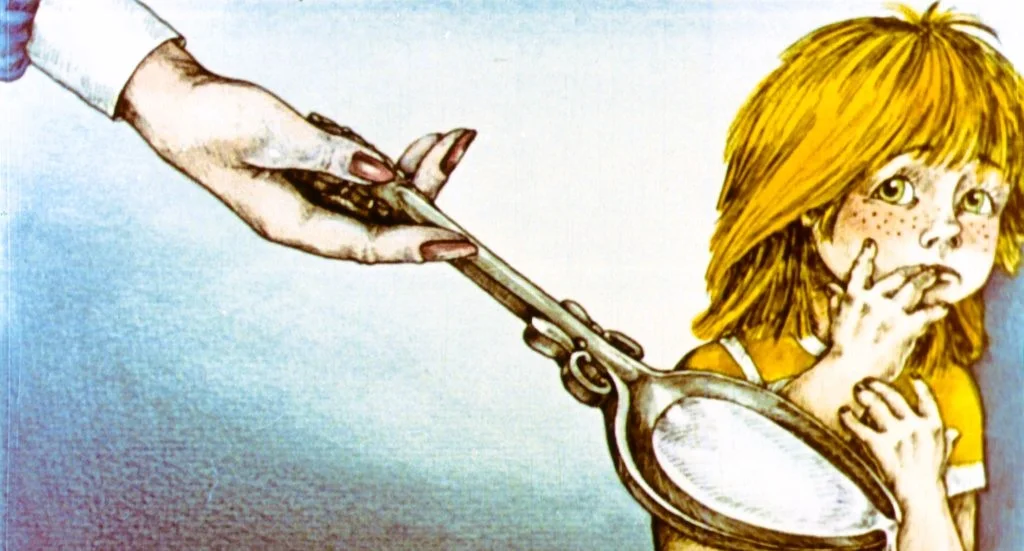 O mână dă o lingură unei fetițe cu părul blond, care pare speriată, stând în fundal cu degetul în gură.