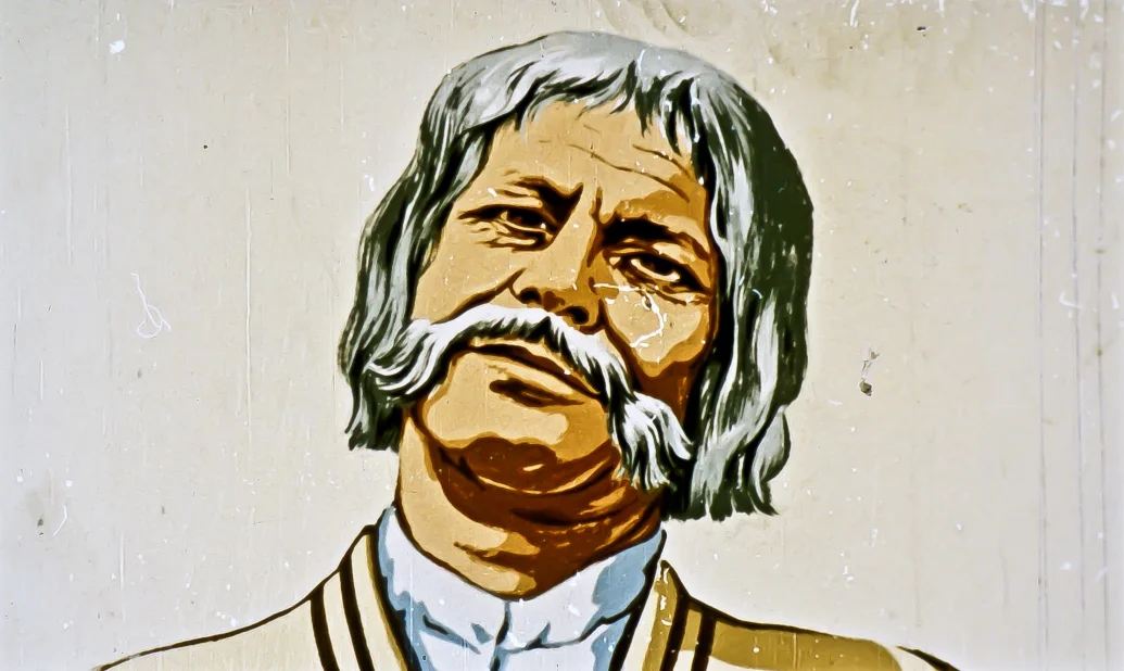 O ilustrație a unui bărbat cu mustață și păr des, care zâmbește.