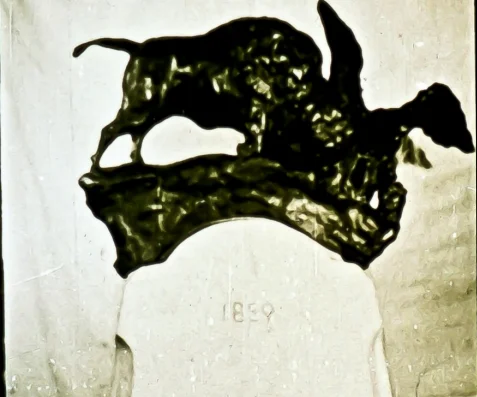 An image depicting a sculpture with a bull and bird on top, featuring the year '1869' engraved below.