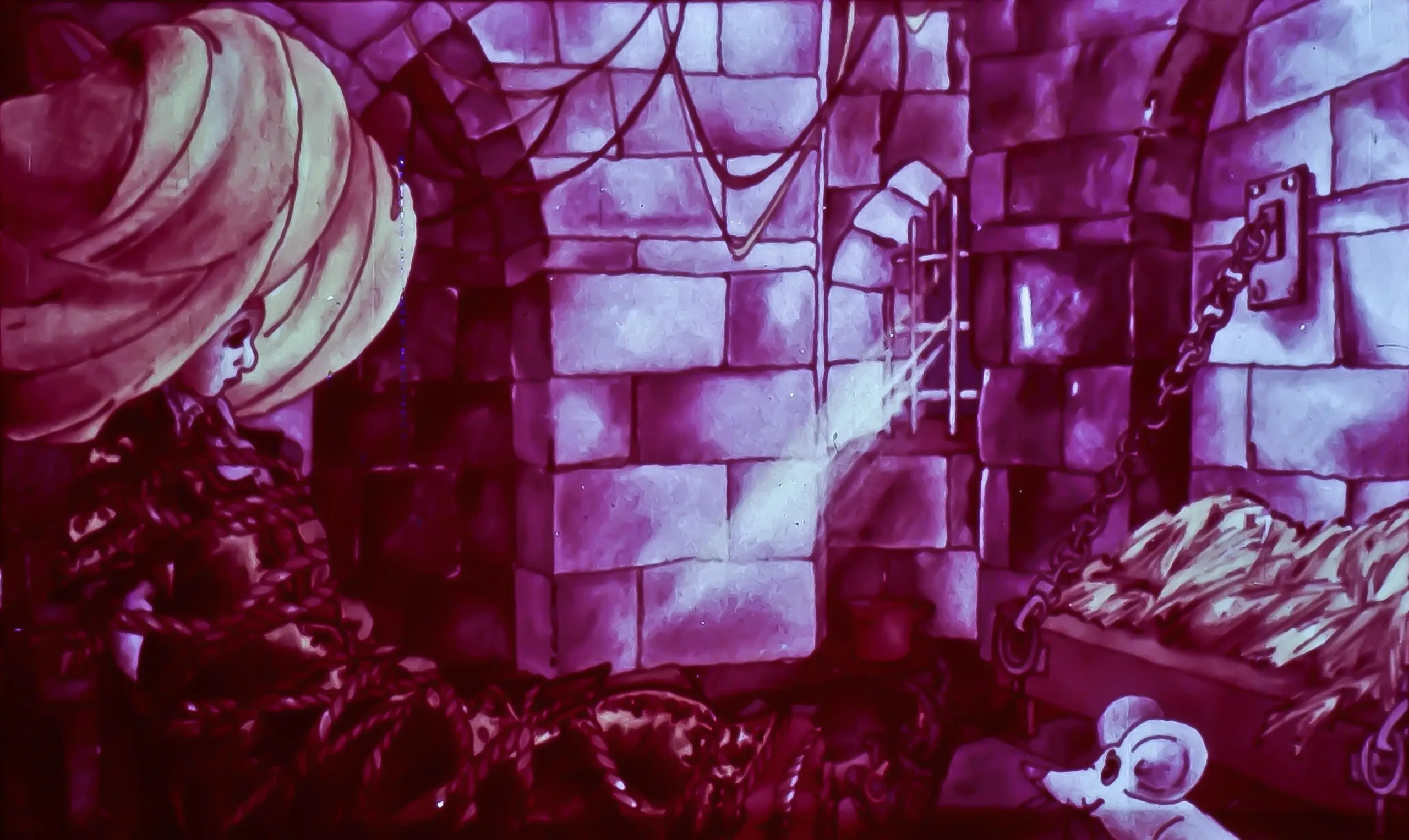 O scenă dintr-o închisoare cu pereți de piatră, o femeie îmbrăcată în haine întunecate stă lângă un pat cu fân, iar un șoarece alb apare în prim-plan.