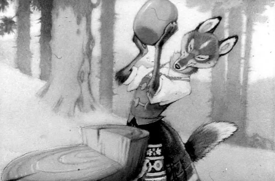 Imagine animată cu un vulpe îmbrăcată în haine tradiționale, ridicând un obiect rotund deasupra capului, în fața unei mese din lemn, în pădure.